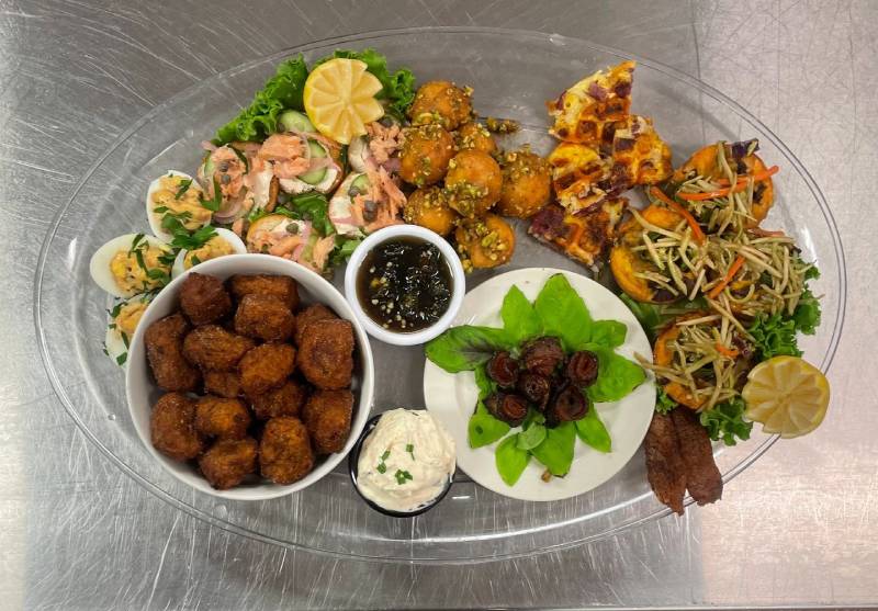 A plate of food that includes shrimp, salad and meatballs.